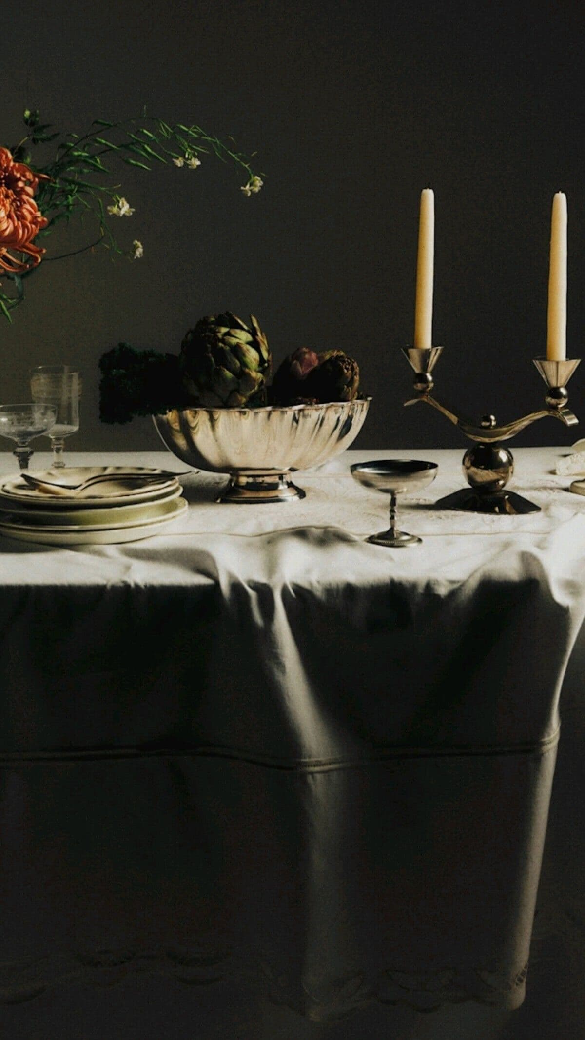Table dressée avec vaisselle, bougies, artichauts et fleurs dans une ambiance chaleureuse